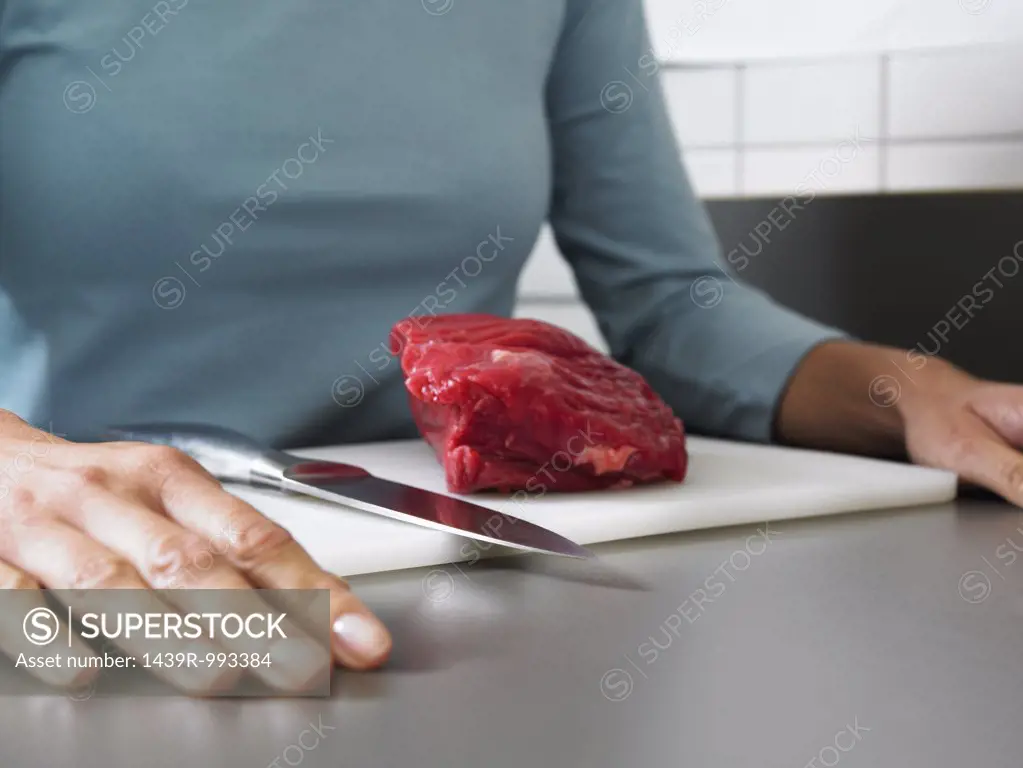 Woman with beef on chopping board