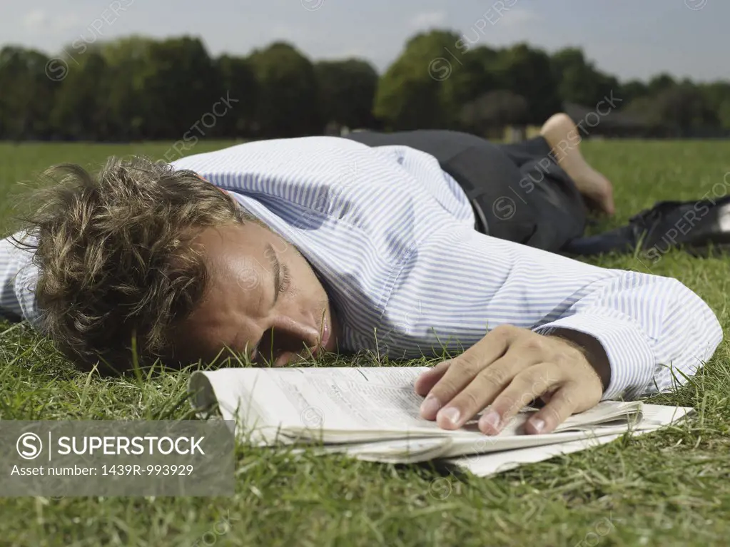 Male office worker sleeping in a park