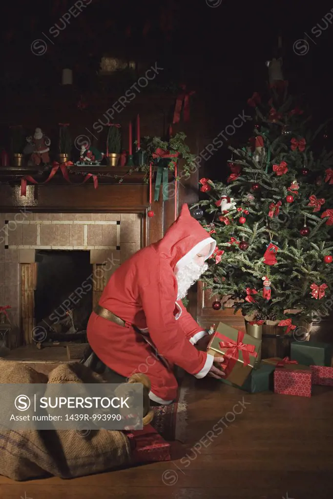 Santa claus placing presents under christmas tree