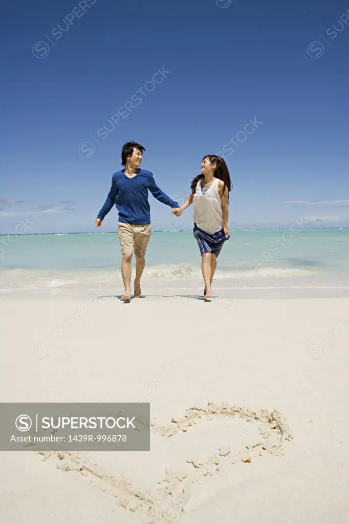 Newlyweds on beach near heart shape