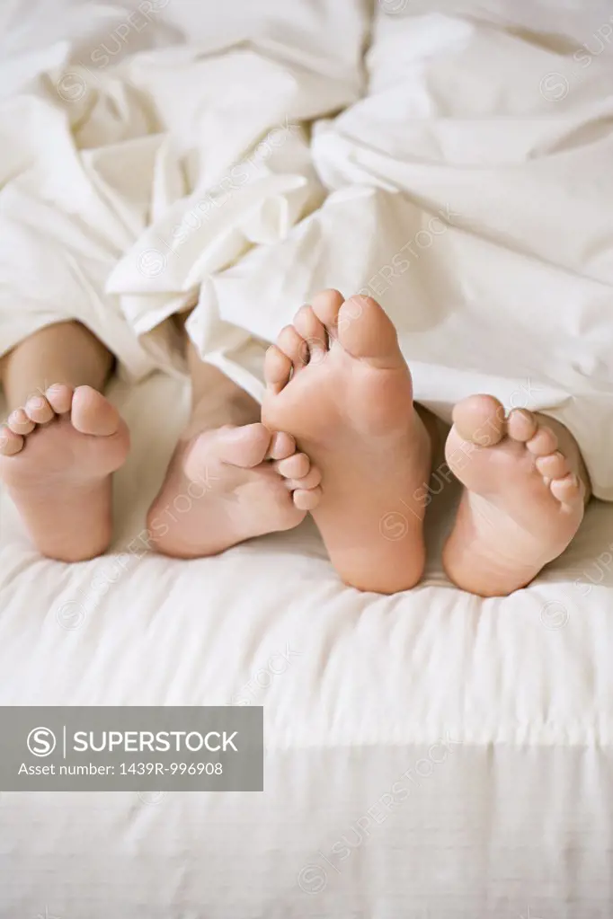 Feet of couple in bed 