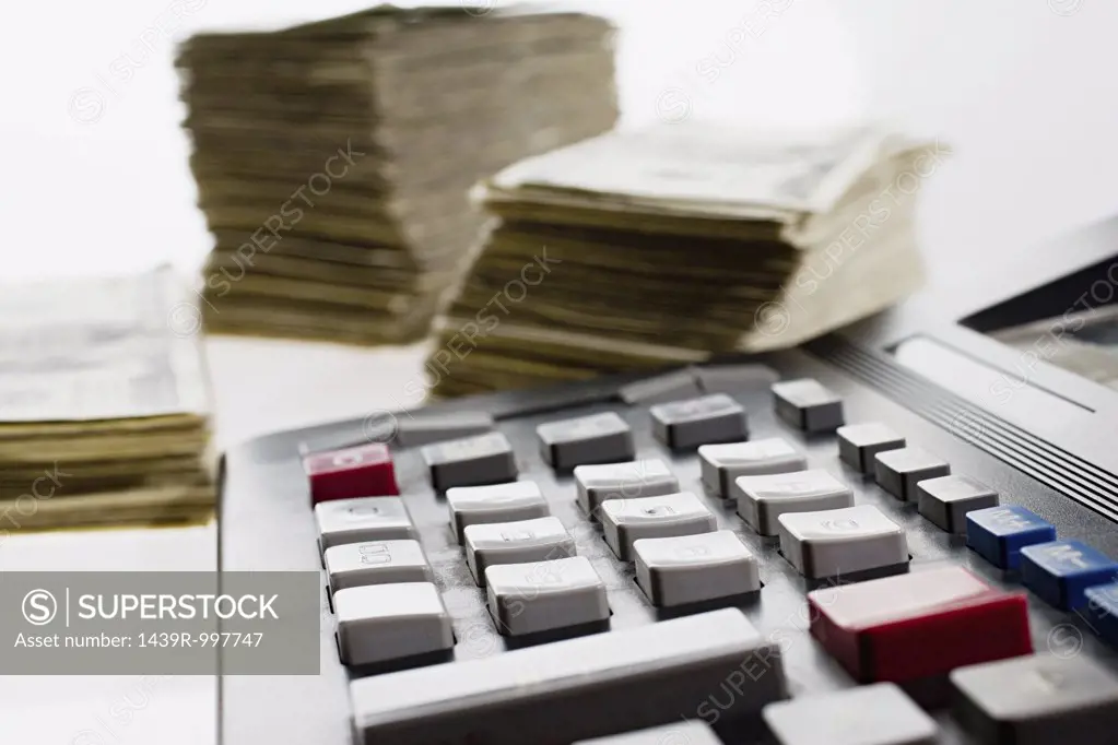Calculator and stacks of banknotes