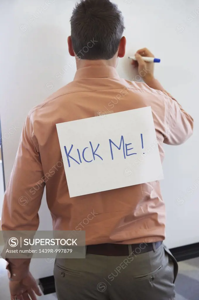 Businessman with kick me sign on his back