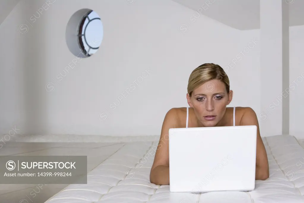 Woman on mattress using laptop