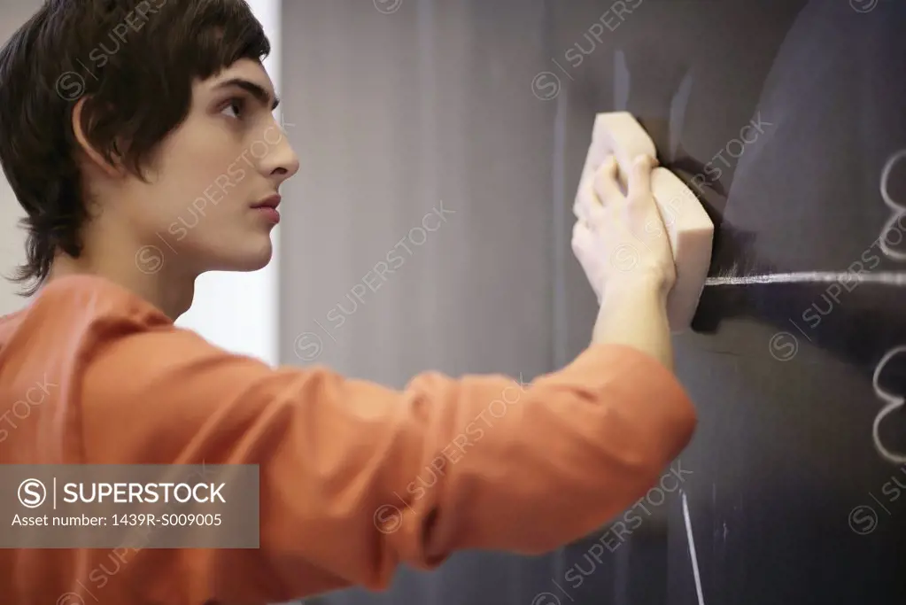 Young man wiping a blackboard