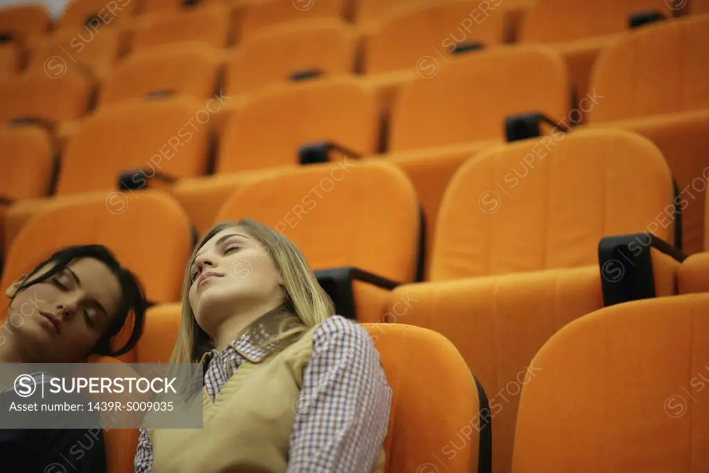Two young women asleep in a lecture theatre
