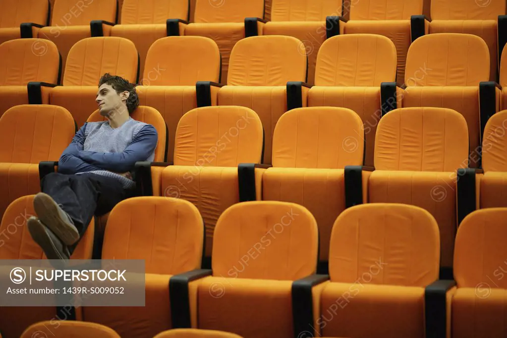 Drowsy young man alone in lecture theatre