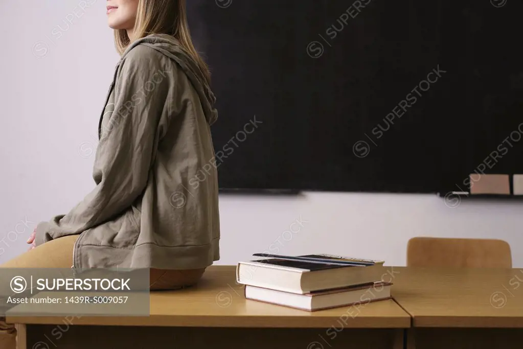 Young woman sitting on edge of desk