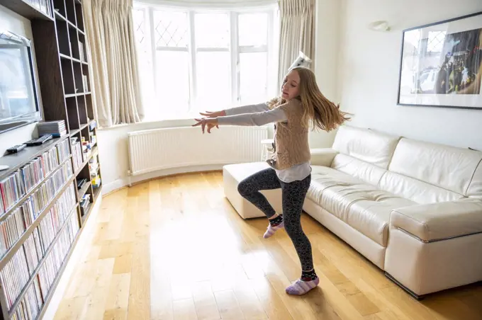 UK, Surrey, Girl dancing in front of TV set in living room