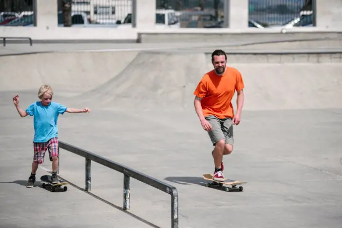 USA, California, Ventura, Father and son (8-9) skateboarding in skate park