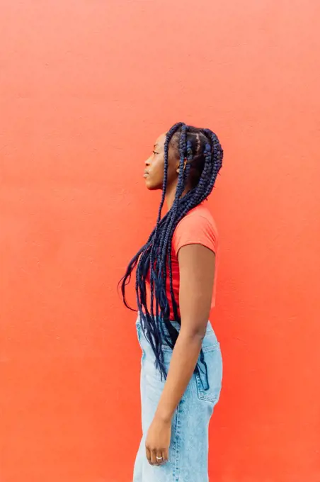 Italy, Milan, Profile of woman with braids against orange wall