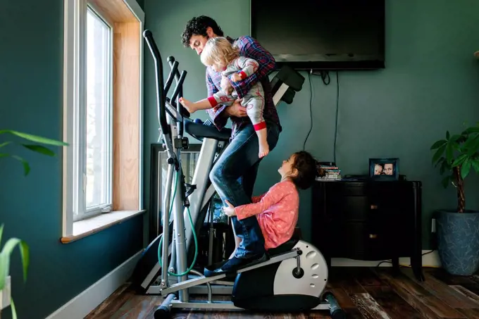Father and children playing on elliptical machine