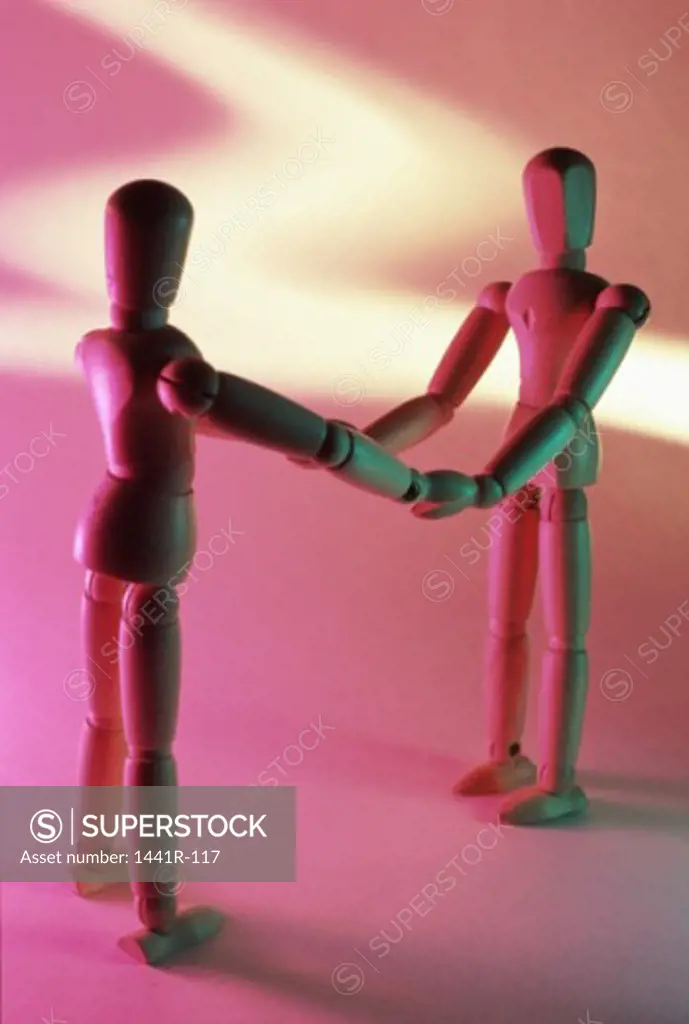 Close-up of two wooden dolls holding hands