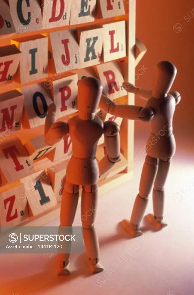 Close-up of two wooden dolls near alphabet blocks