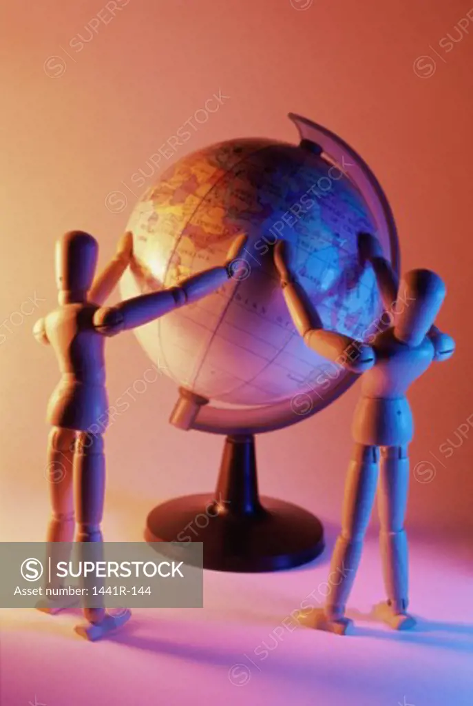 Close-up of two wooden dolls near a globe