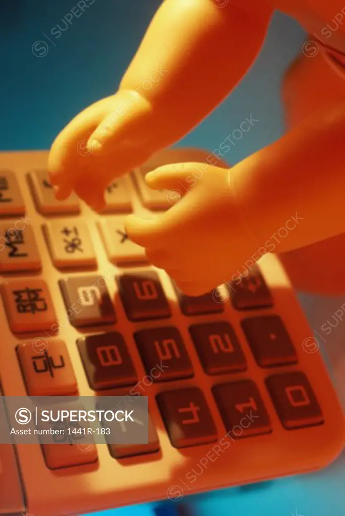 Hands of a doll on a calculator