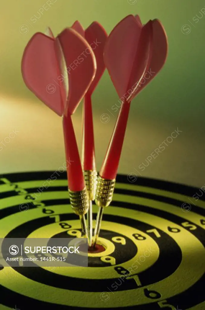 Close-up of three darts in the bull's-eye of a dartboard
