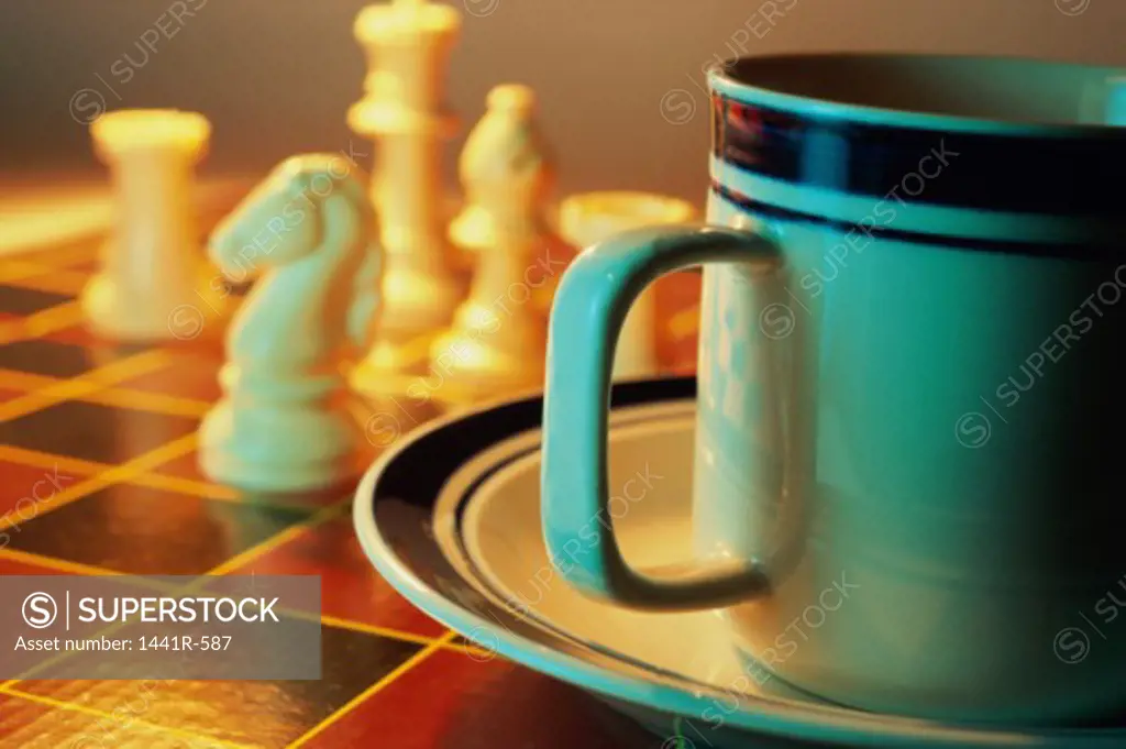 Close-up of a cup and a saucer on a chess board