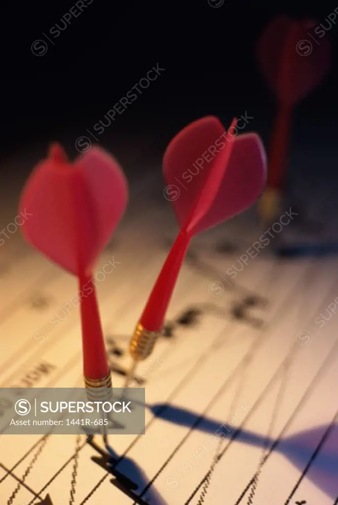 Close-up of two darts on a financial report