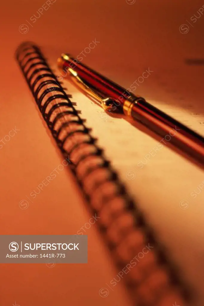 Close-up of a ballpoint pen on a spiral bound notebook
