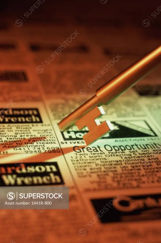 Close-up of a key on a real estate newspaper