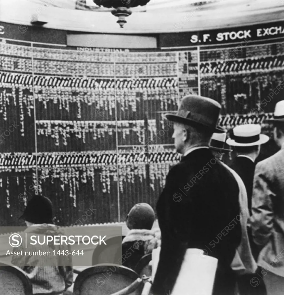 Rear view of shareholders in a stock exchange looking at a stock market data, 1929