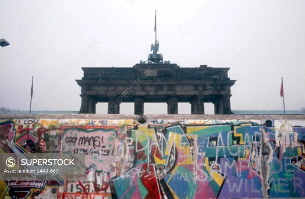 Graffiti on a wall with a memorial gate in background, Berlin Wall, Brandenburg Gate, Berlin, Germany