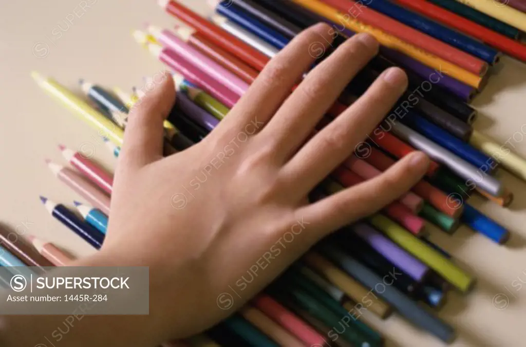 Close-up of a person's hand on colored pencils