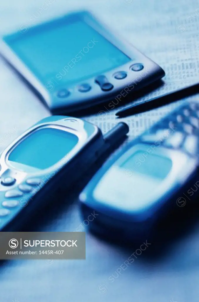 Close-up of two mobile phones and a hand held device
