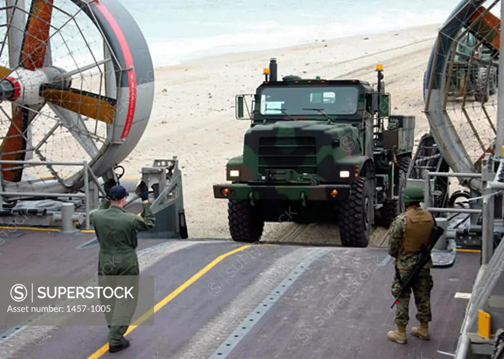 Rear view of two Navy soldiers guiding a truck for boarding onto a landing craft, Camp Lejeune, North Carolina, USA, April 12, 2005