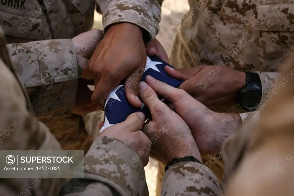 Marines fold an American flag after it was raised in memory of a fallen soldier