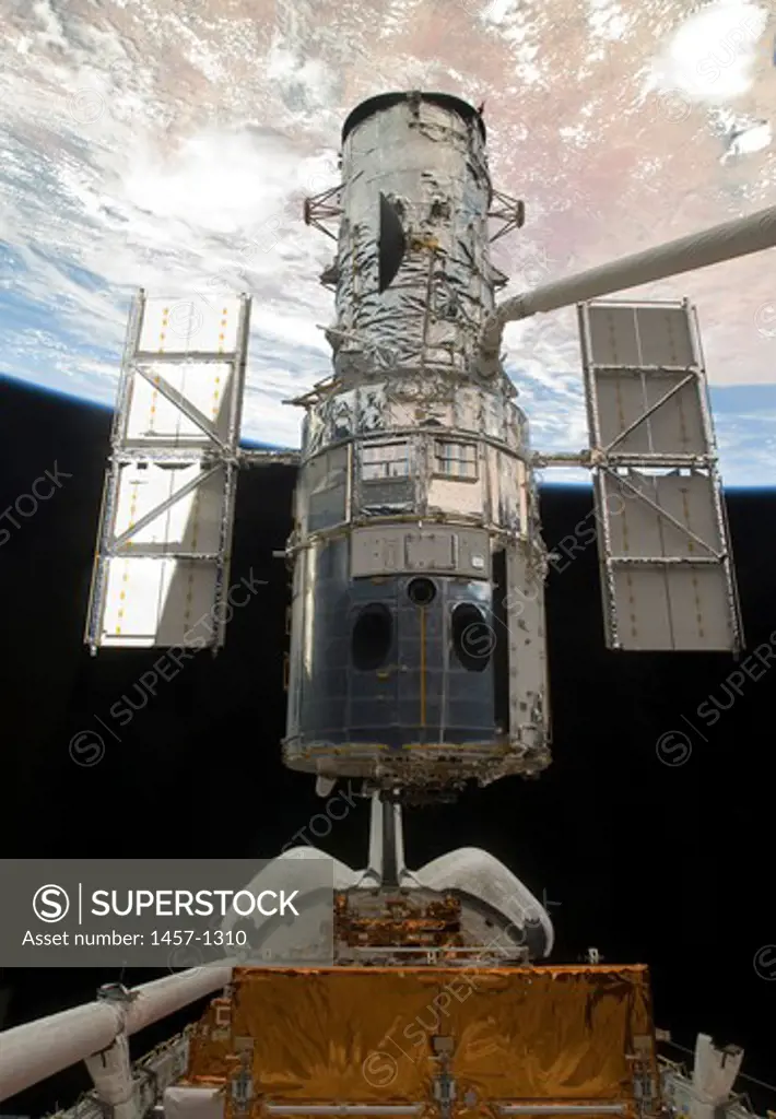 The Space Shuttle Atlantis' arm lifts the Hubble Space Telescope from the cargo bay