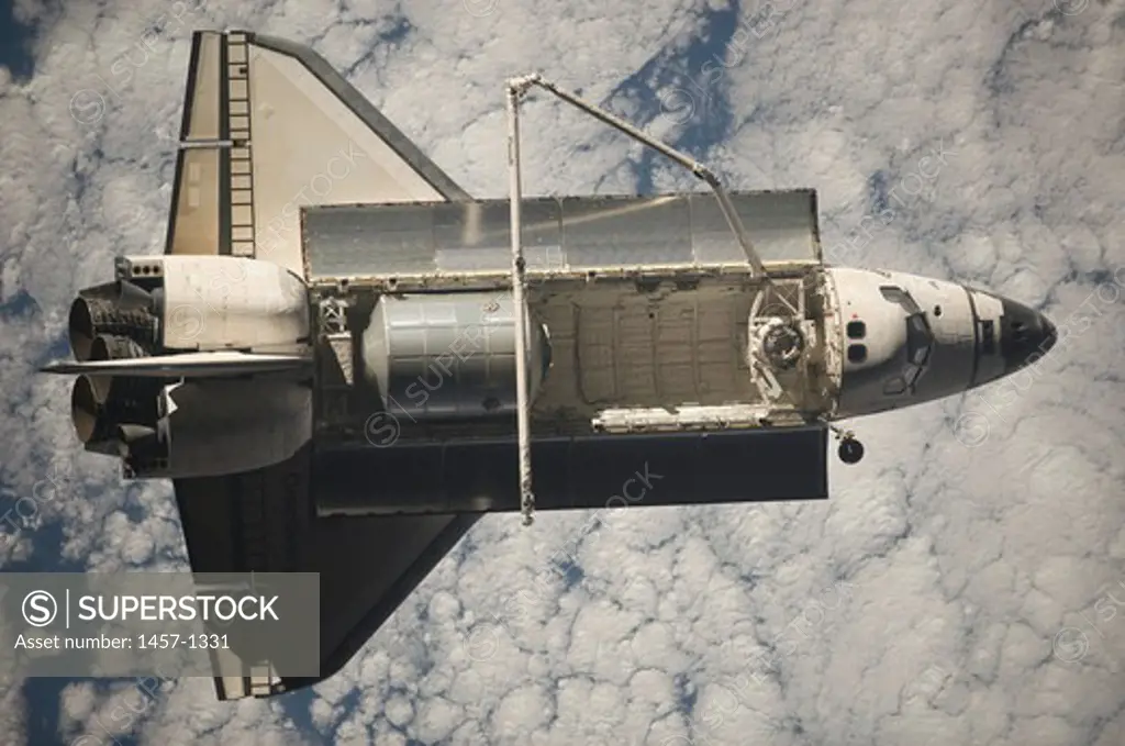 Backdropped by a cloud-covered part of Earth, Space Shuttle Discovery