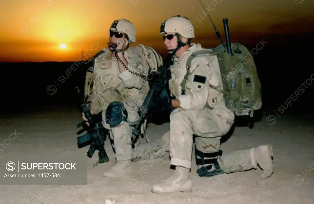 Two soldiers kneeling on the ground at dusk
