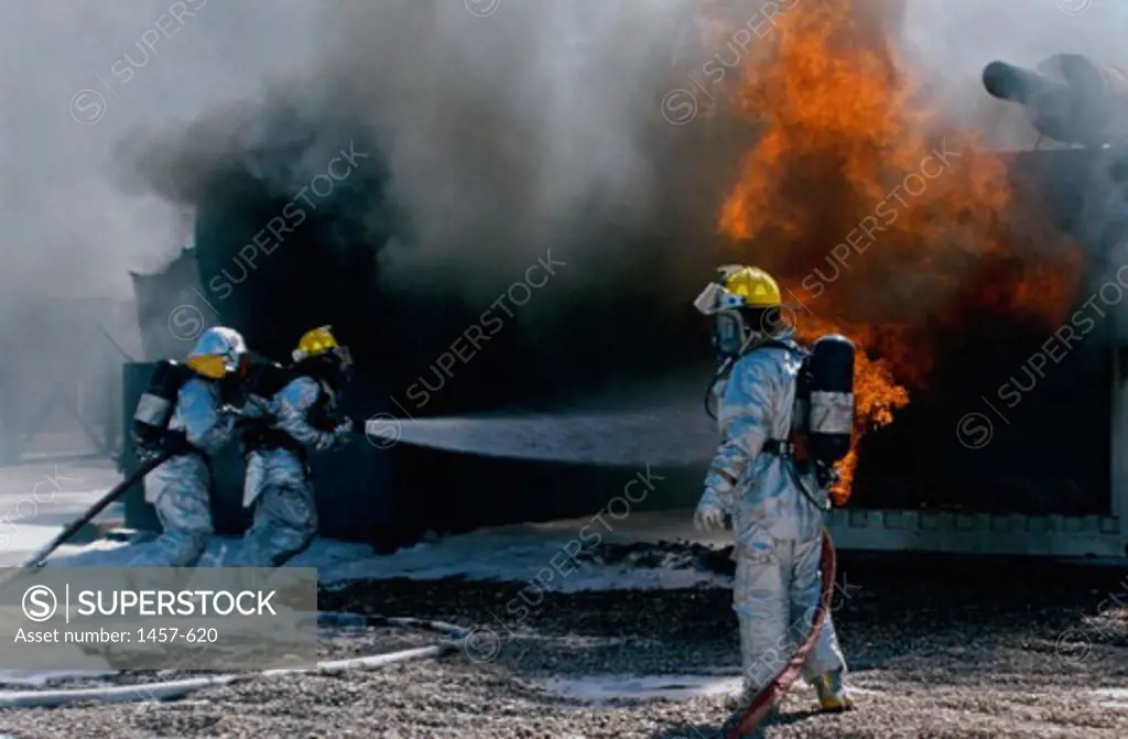 Three firefighters extinguishing a fire