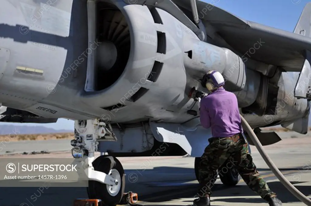 Aviation fuel technician attaches a fuel line to an AV-8B Harrier.