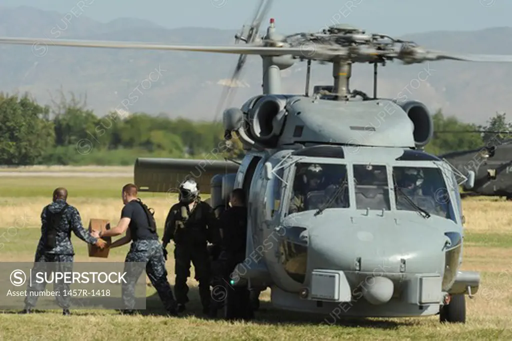 U.S. Navy sailors load humanitarian supplies onto a Navy HH-60 Pave Hawk helicopter.