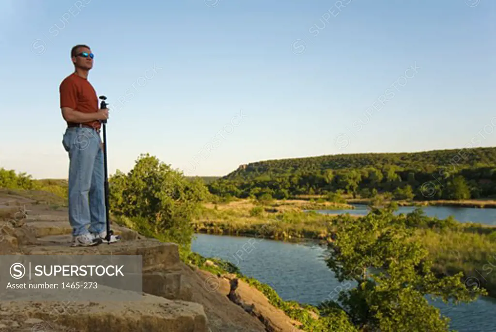 Mature man standing on a cliff at the riverside, Brazos River, Texas, USA
