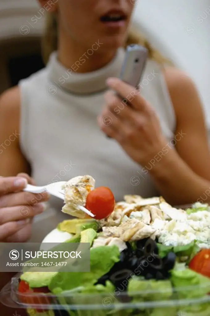 Mid section view of a young woman eating salad