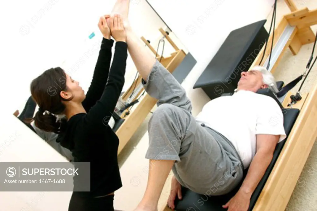 Female instructor helping a senior man exercise