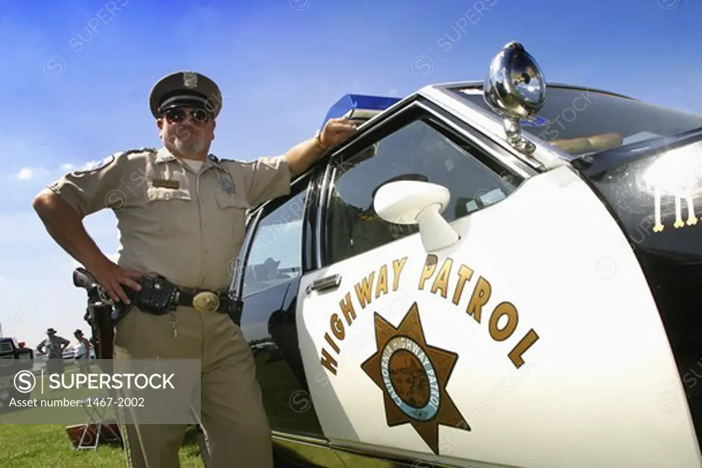 Low angle view of a police officer standing next to a car