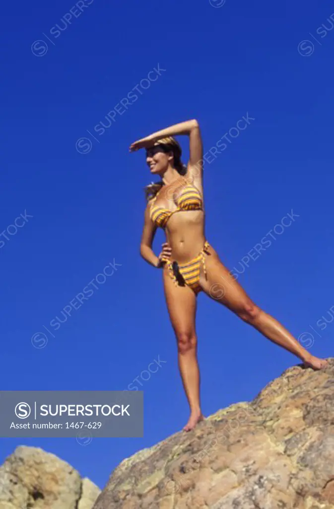 Low angle view of a young woman standing on a rock