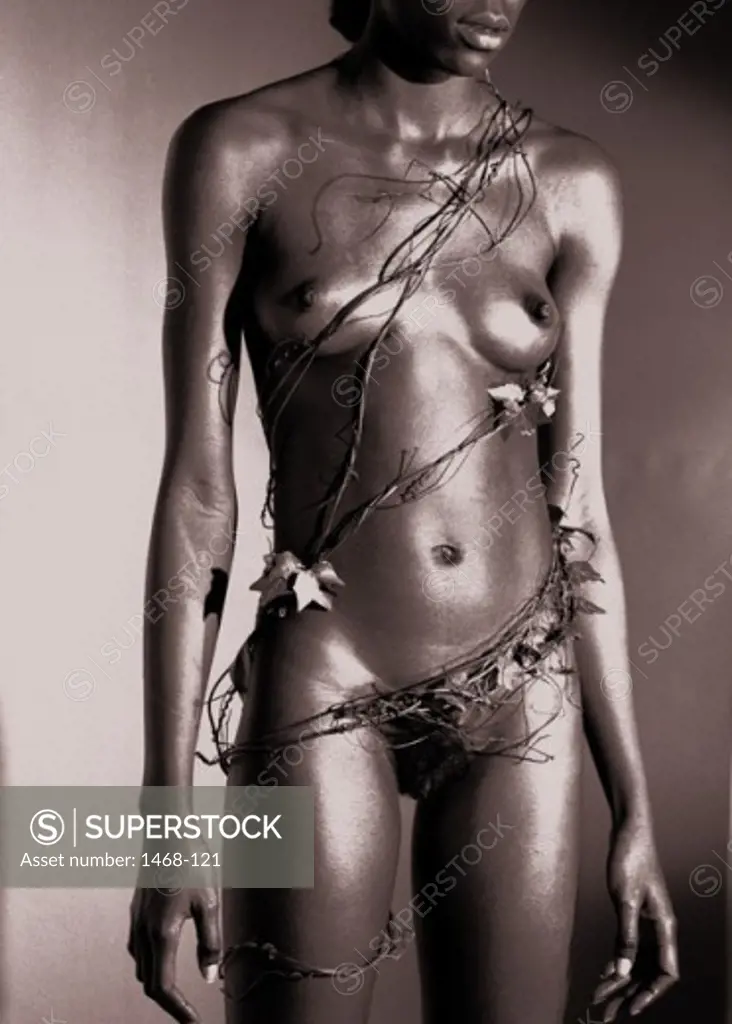Close-up of a naked young woman with ivy wrapped around her body