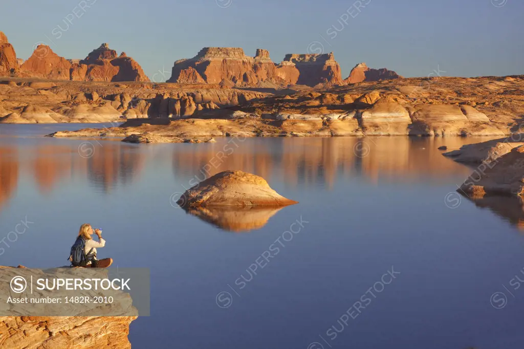 Woman drinking water near a lake, Lake Powell, Face Canyon, Glen Canyon National Recreation Area, Utah, USA
