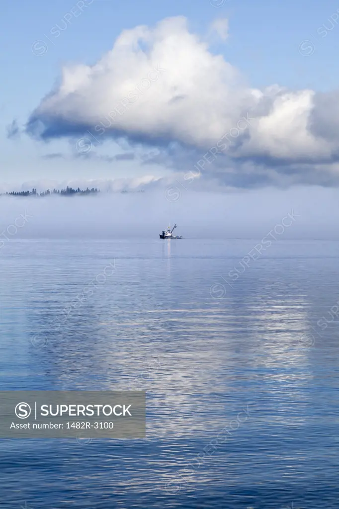 Fishing boat with morning clouds and fog in Hood Canal, Washington State, USA
