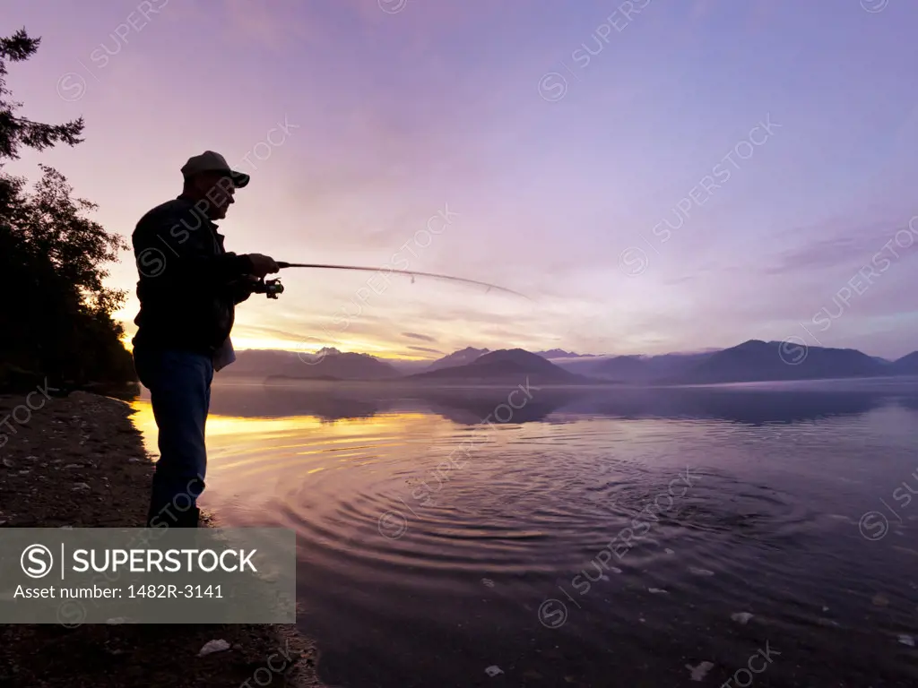 Man catching a fish at sunset, Hood Canal, Washington State, USA