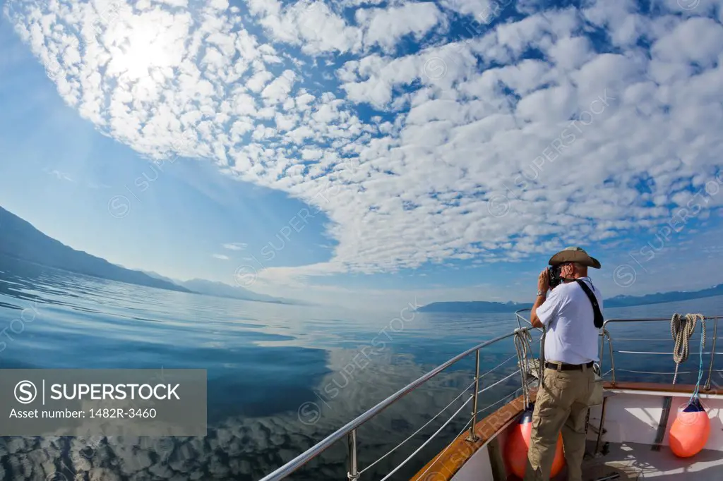 Man photographing from a boat, Freshwater Bay, Alaska, USA