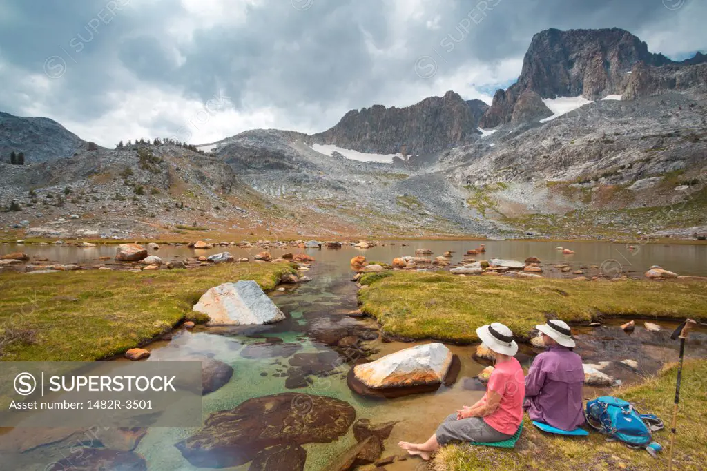 Hikers resting along stream above a lake, Garnet Lake, Ansel Adams Wilderness, Inyo National Forest, California, USA