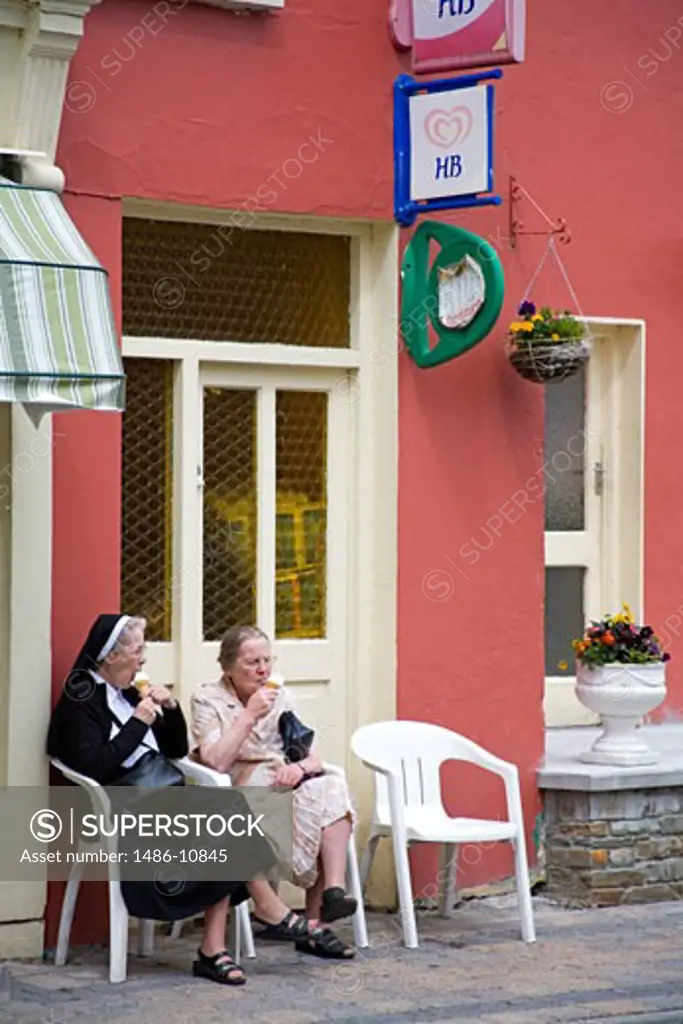 Two senior women eating ice creams outside an ice cream parlor, Glengarriff, County Cork, Munster Province, Ireland