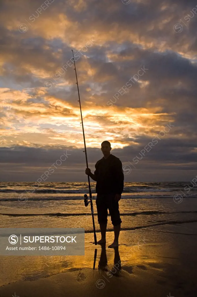 Silhouette of a man standing on the beach and holding a fishing rod, Fanore Beach, Fanore, County Clare, Munster Province, Ireland